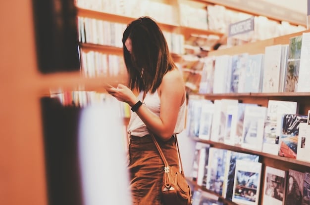 A close-up shot of someone browsing through shelves of used manga in a used bookstore. The focus is on the variety of titles and the slightly worn condition of the manga.